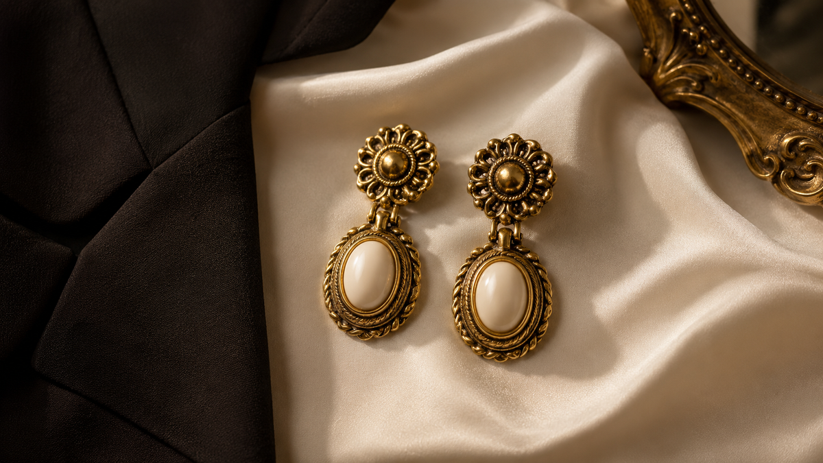 Vintage-inspired statement earrings styled with ivory silk and a black blazer.