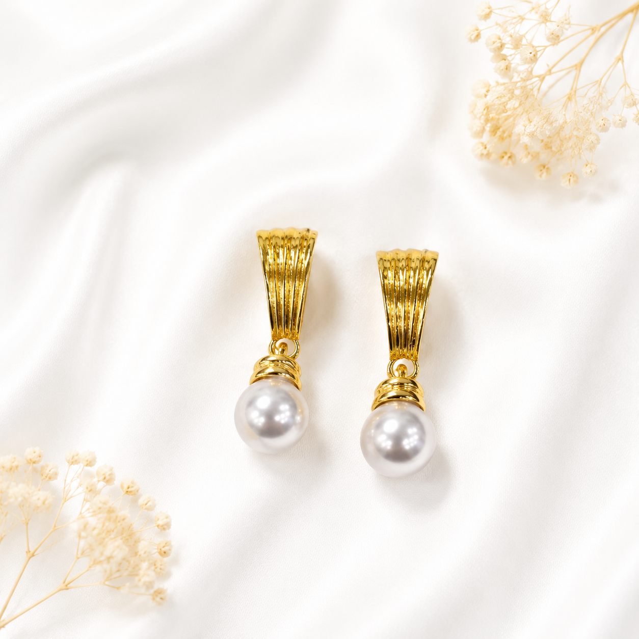 White pearl-style drop stud earrings with a gold-tone finish.
