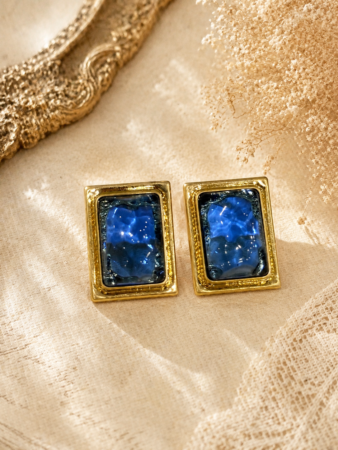 Gold-tone rectangular blue glass-style stud earrings front view