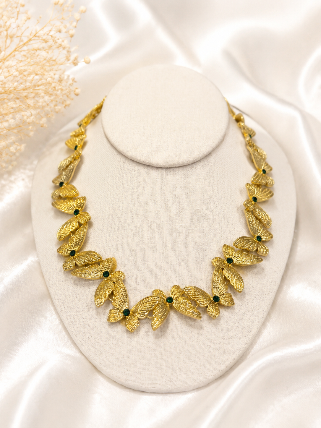 Gold-tone butterfly necklace detail with green stone-style accents