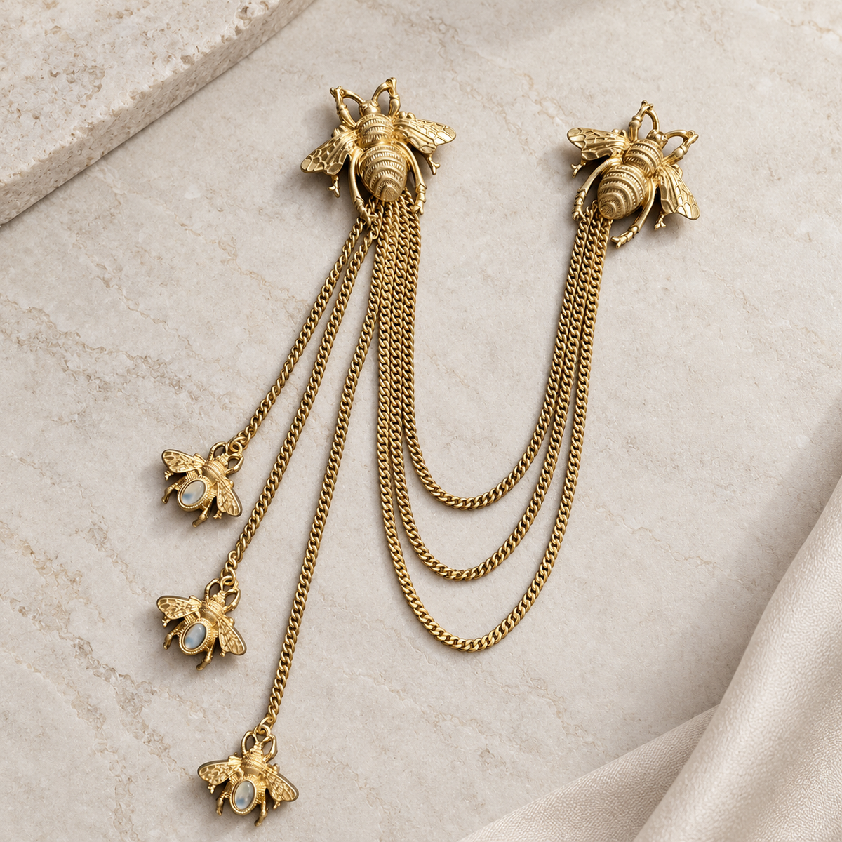 Two gold-tone bee motifs joined by three draped chains, with three additional chain tassels ending in small bee charms
