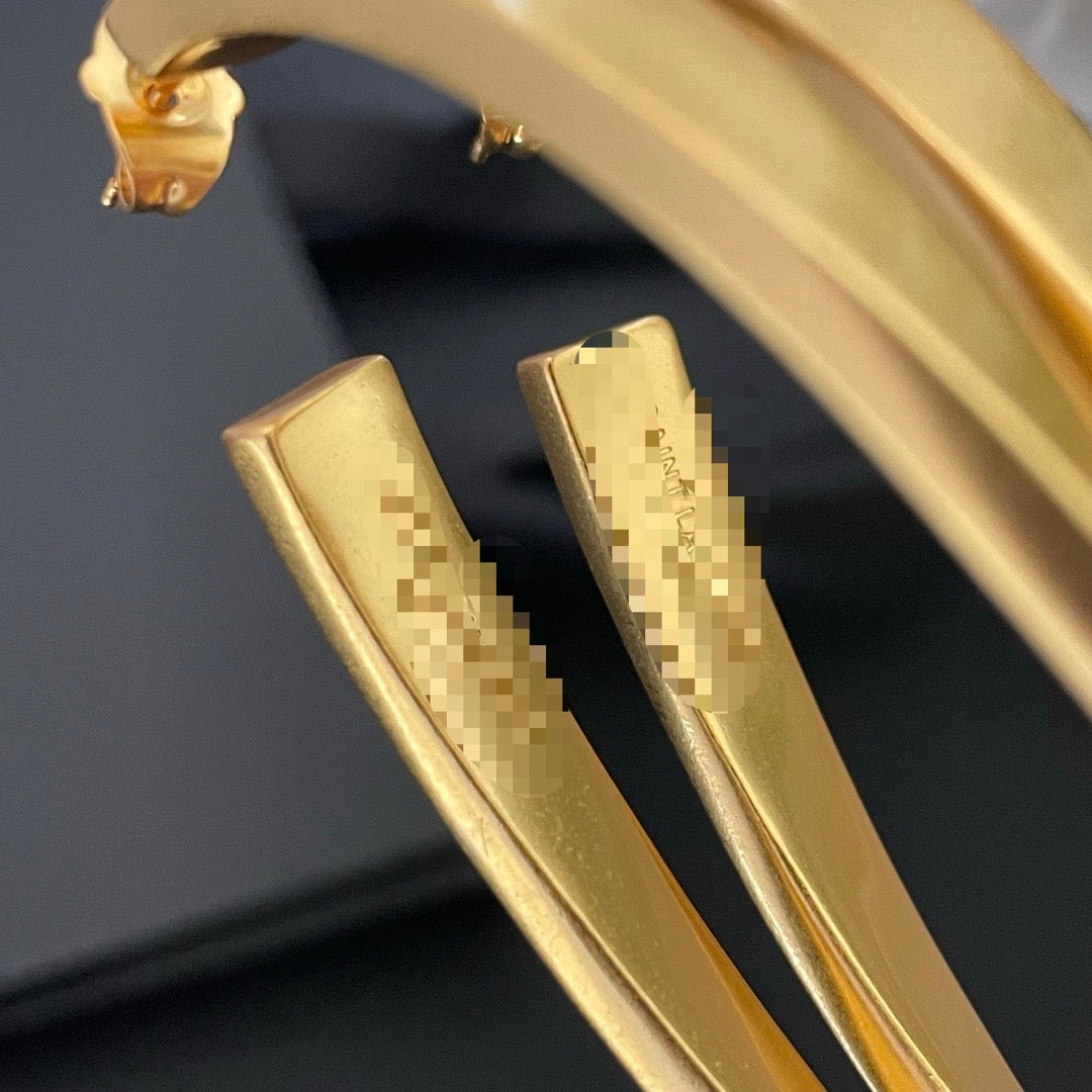 Detail view of the curved gold-tone finish on sculptural long stud earrings