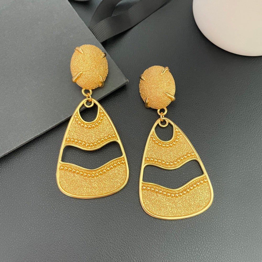 18K gold-plated textured openwork drop clip-on earrings on a black surface