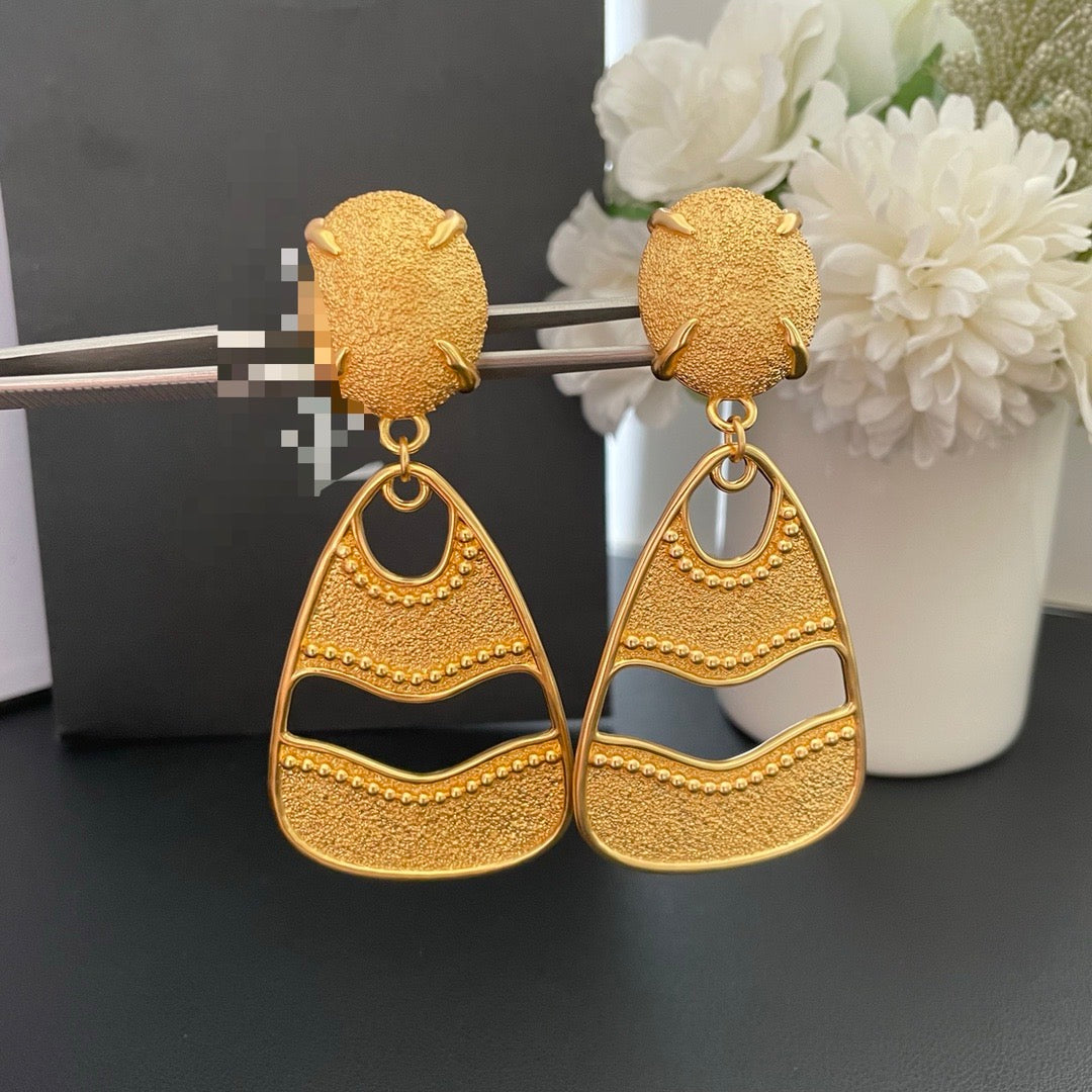 Front view of gold-tone textured openwork drop clip-on earrings