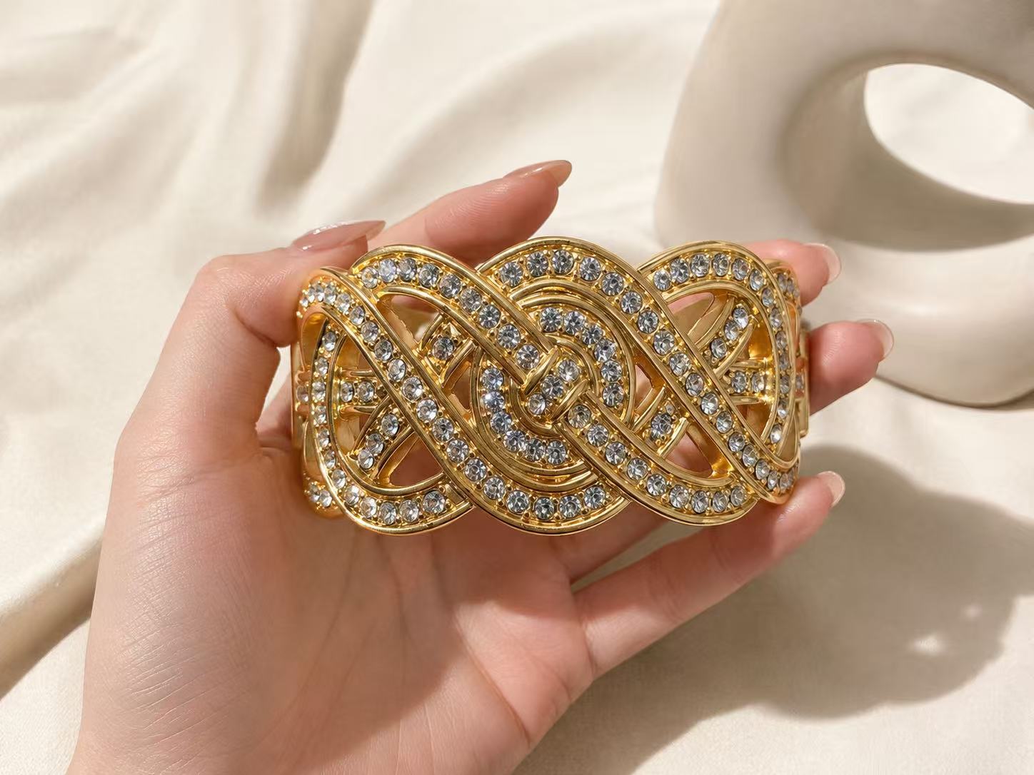 Gold-tone crystal-style interwoven ribbon statement cuff bracelet close-up