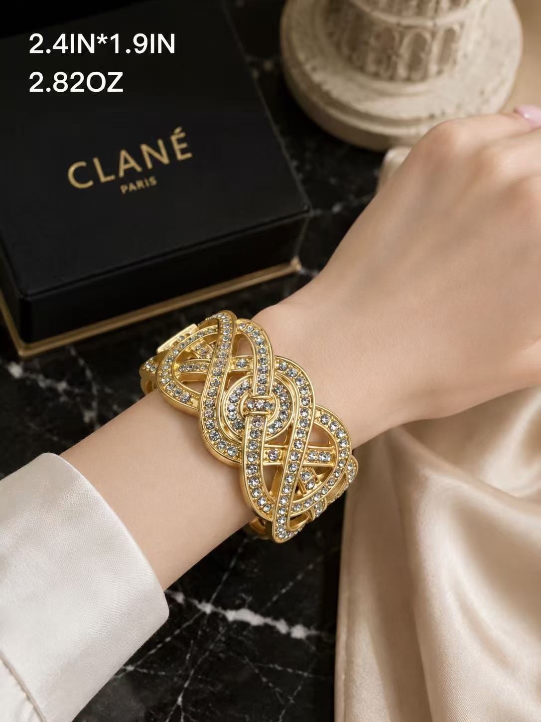 Gold-tone crystal-style interwoven ribbon statement cuff bracelet worn on wrist