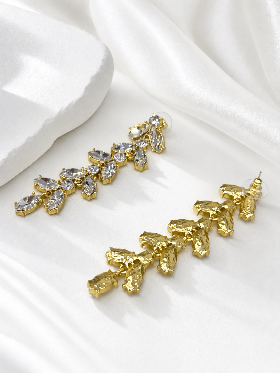 Front and back view of clear gold-tone leaf rhinestone drop stud earrings showing stud posts