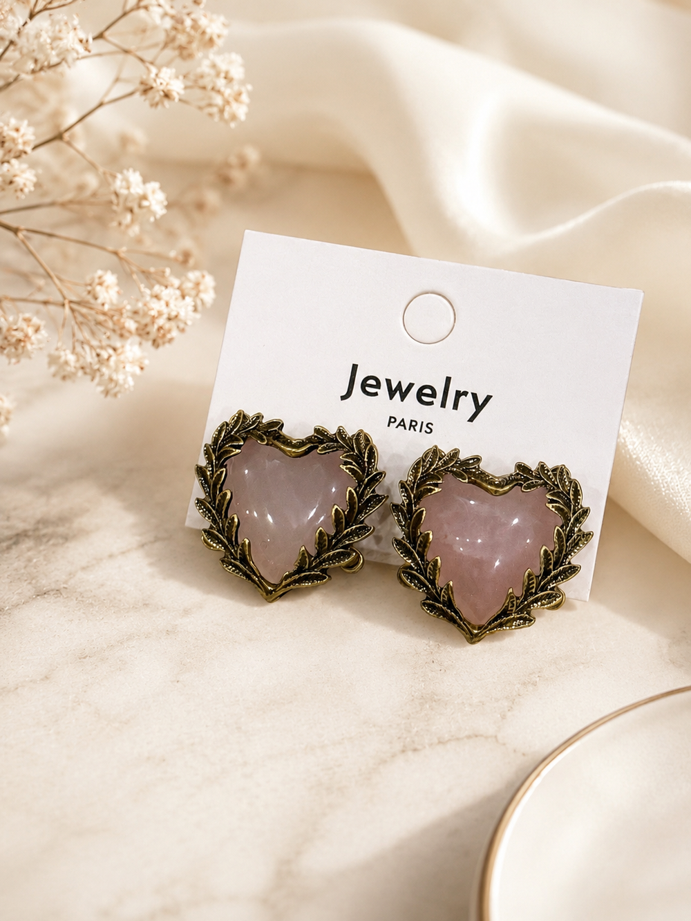 Pink crystal-style heart stud earrings with a leaf-inspired gold-tone frame