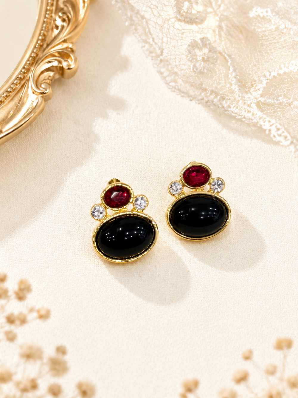 Pair of gold-tone clip-on earrings with black oval, red, and clear stone-style accents