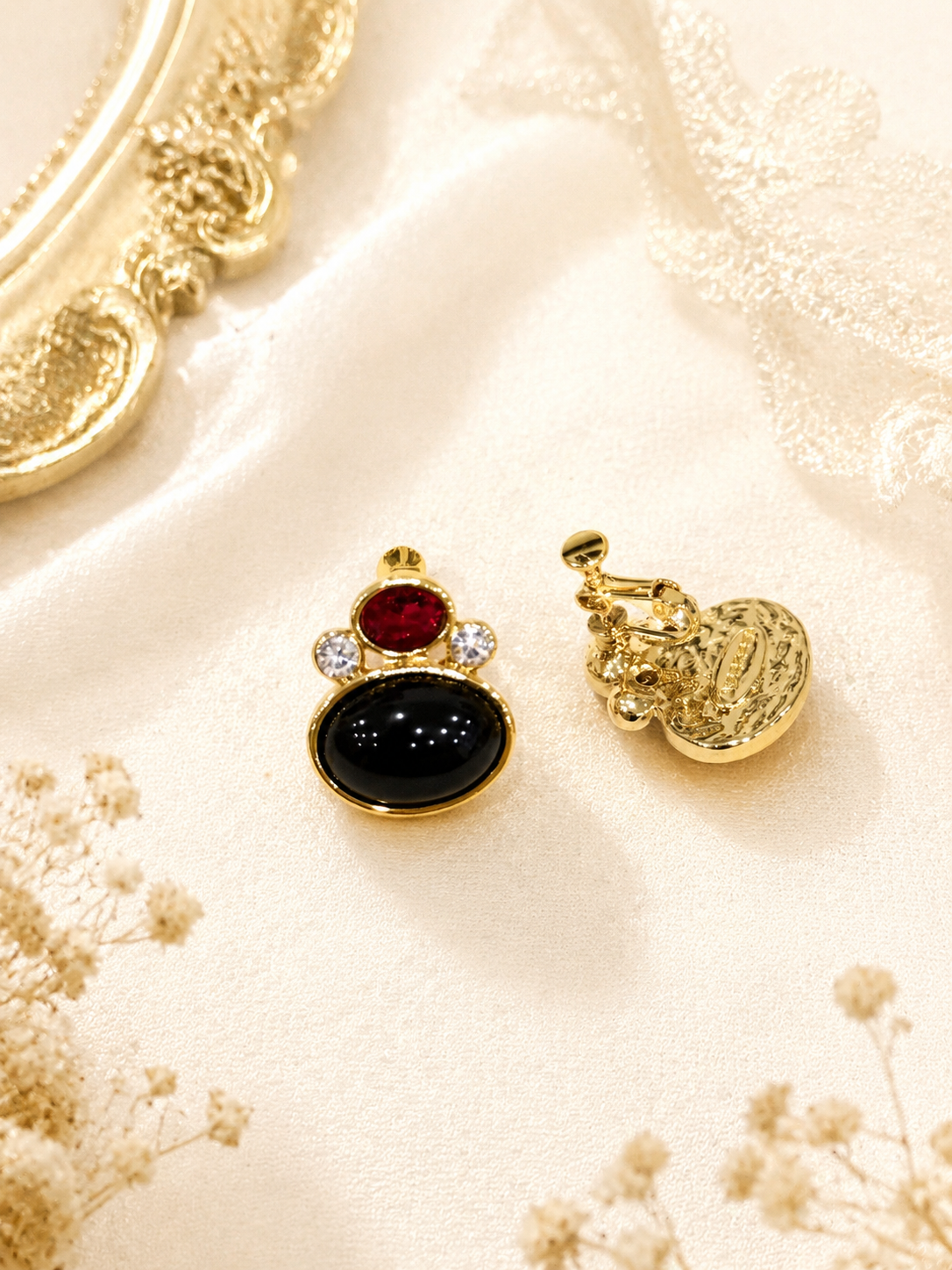 Front and back view of a gold-tone black and red stone-style clip-on earring
