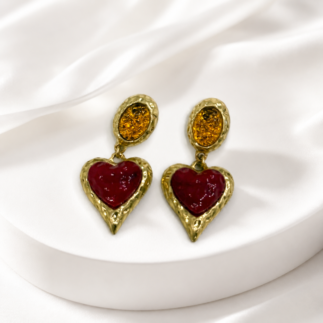 Red glass heart drop earrings with a gold-tone setting.