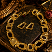 Back view of gold-tone red stone-style necklace and stud earrings with textured metal detail