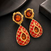 Orange-red colorway dangle clip-on earrings with textured gold-tone frame, detail view