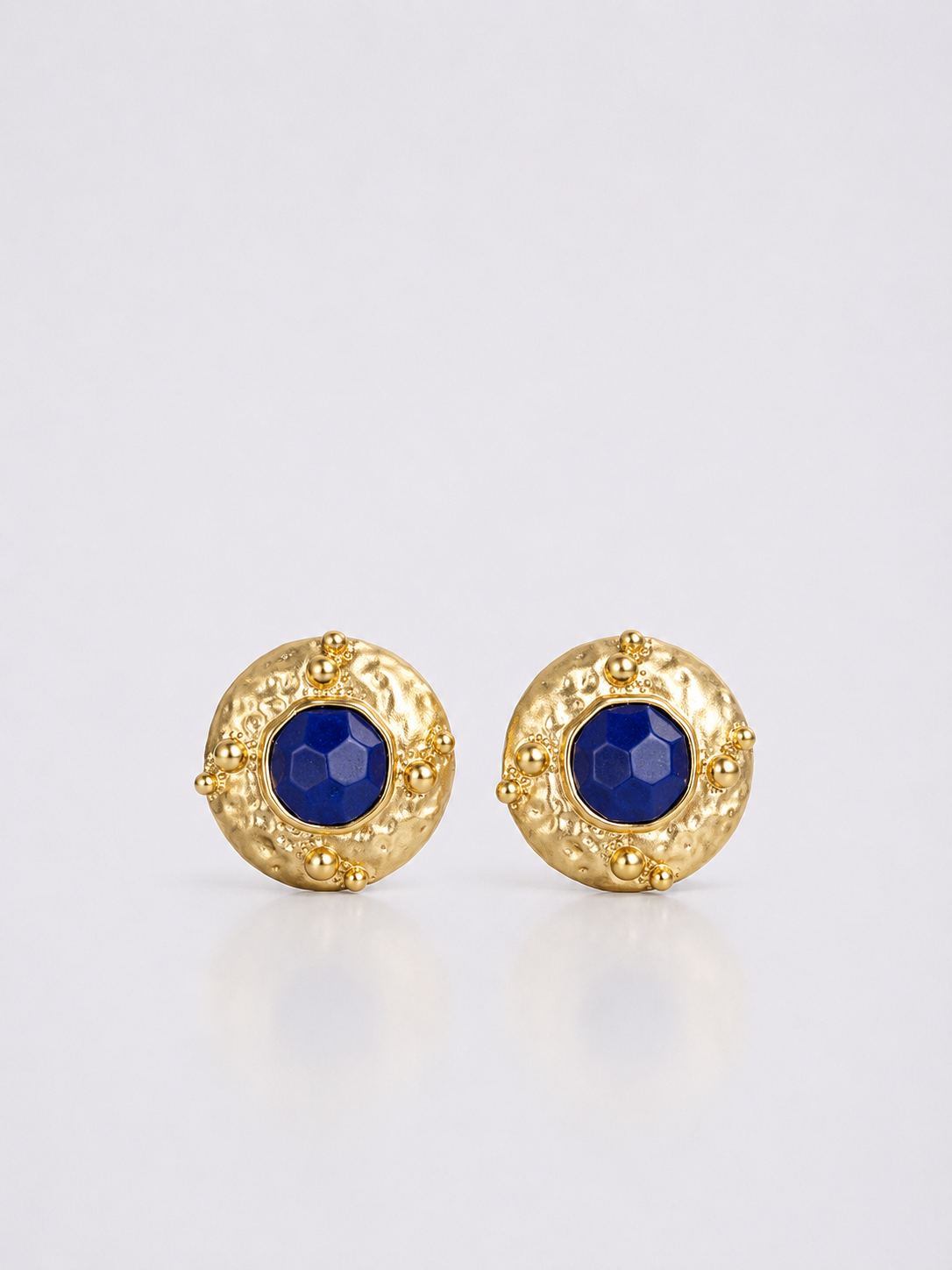 Textured gold-tone clip-on statement earrings with deep blue centers front view