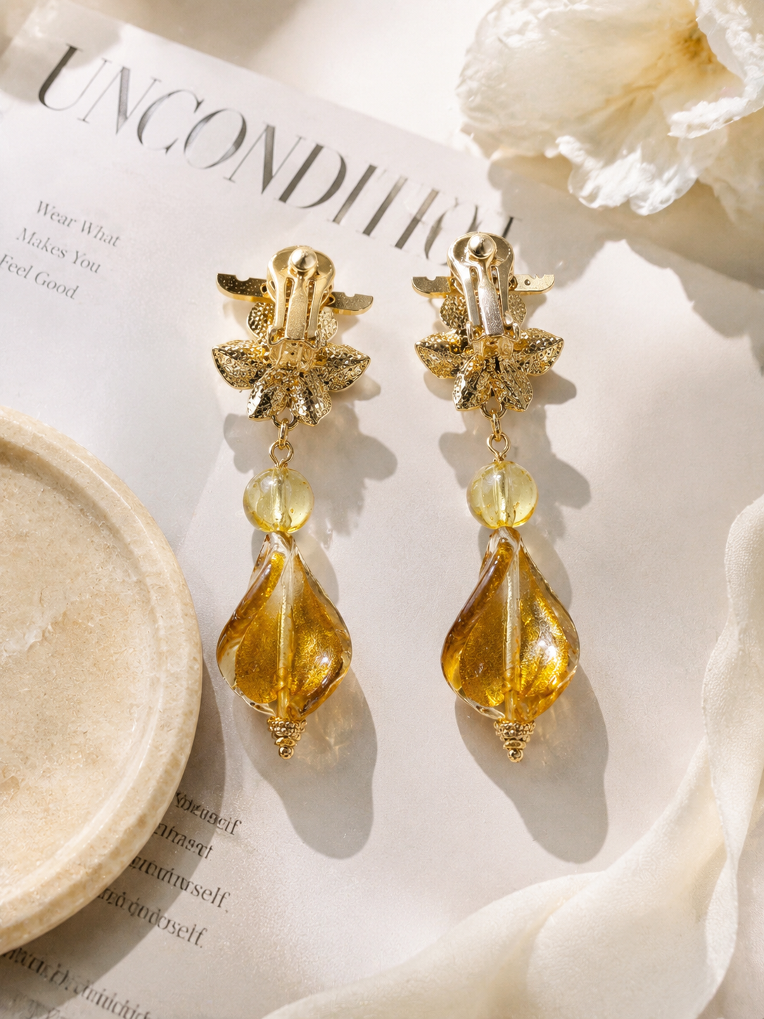 Gold-tone floral clip-on drop earrings with amber-tone accents detail view