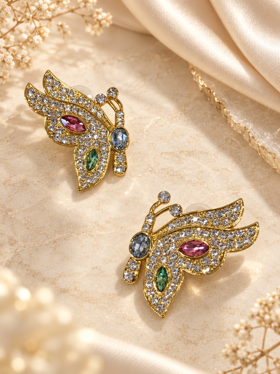 Angled view of gold-tone butterfly stud earrings with colorful faceted details