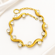 Gold-tone sculptural wave bracelet with clear faceted crystal-style accents