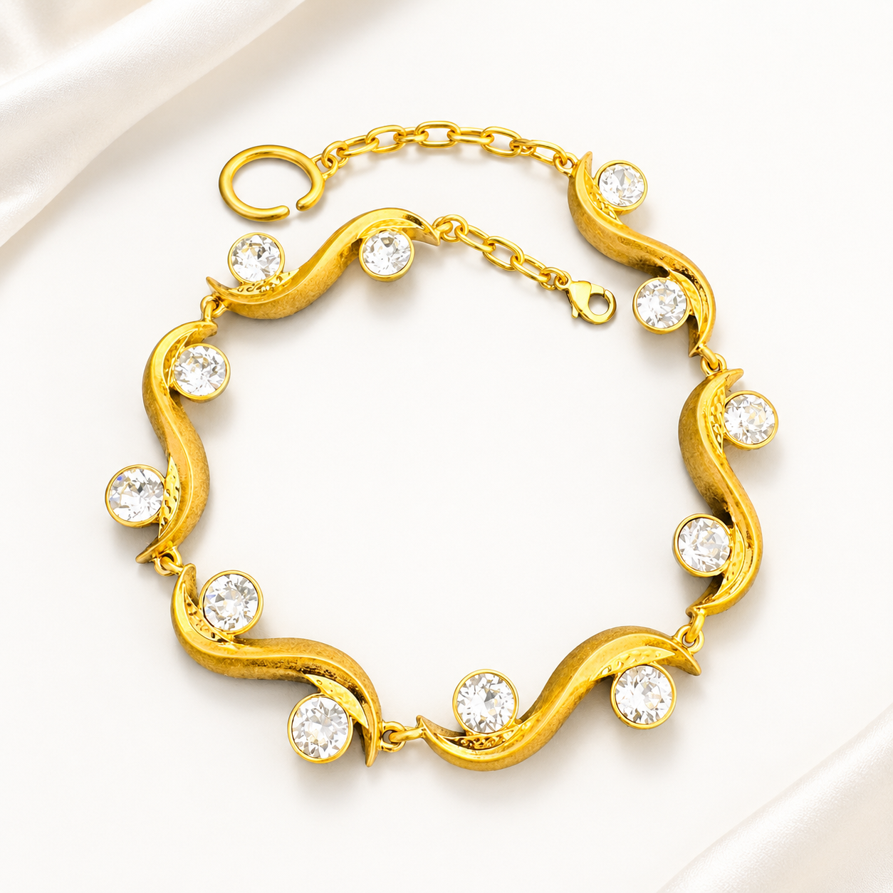 Gold-tone sculptural wave bracelet with clear faceted crystal-style accents