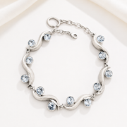 Silver-tone sculptural wave bracelet with gray faceted crystal-style accents