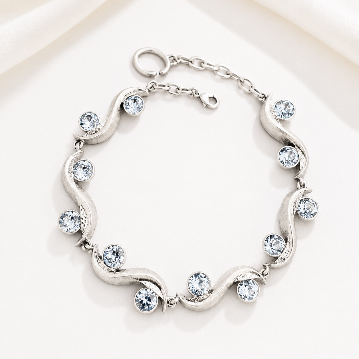 Silver-tone sculptural wave bracelet with gray faceted crystal-style accents