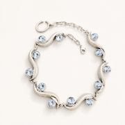 Silver-tone sculptural wave bracelet with light blue faceted crystal-style accents