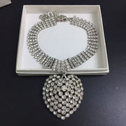 Silver-tone rhinestone choker necklace with a large heart pendant and an extender chain.