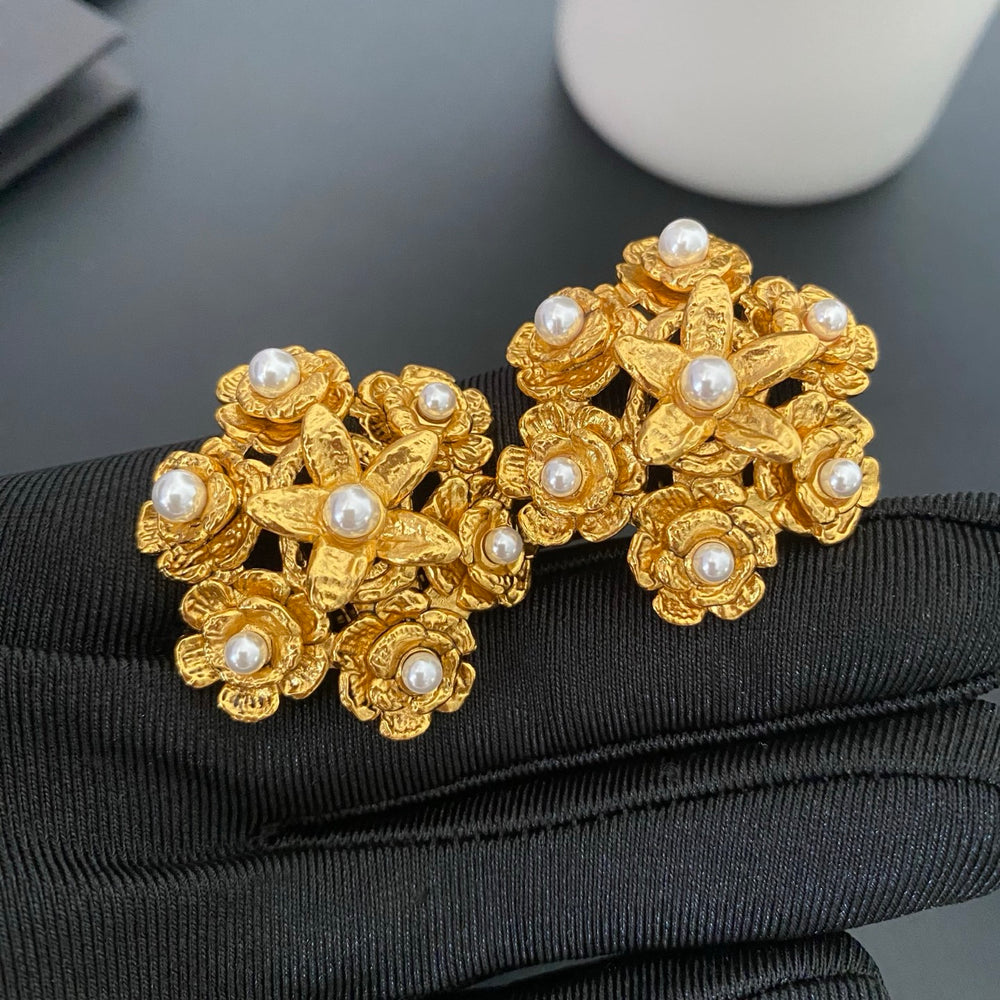 Front view of gold floral pearl clip-on earrings with textured petals and white pearl accents.