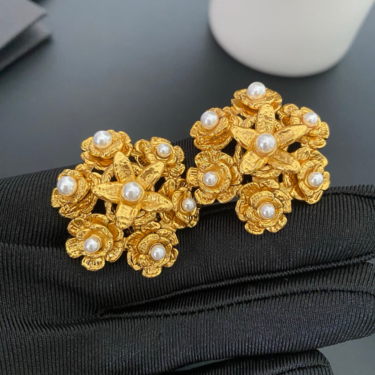 Front view of gold floral pearl clip-on earrings with textured petals and white pearl accents.