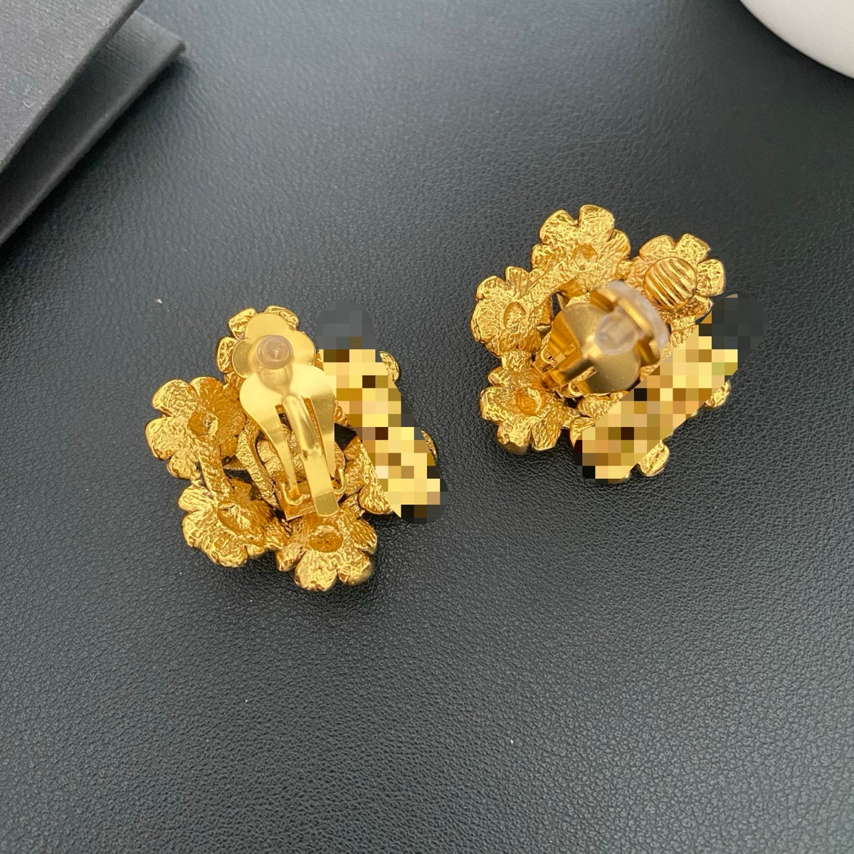 Back view of gold floral earrings showing the clip-on fastenings.