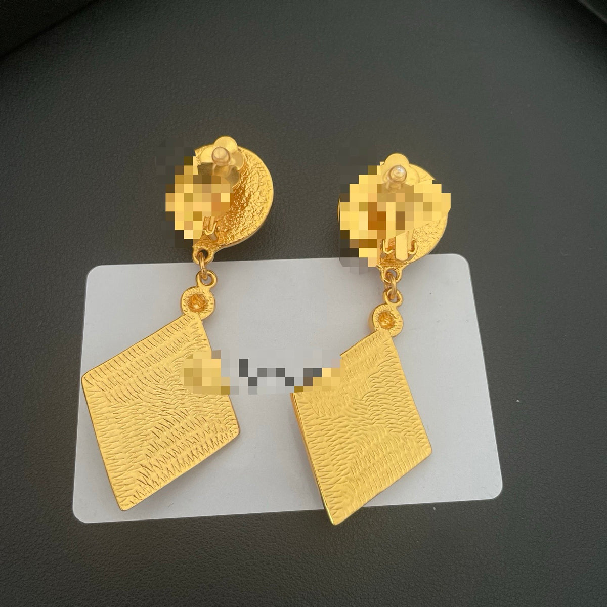 Back view of the red enamel and resin drop earrings showing the clip-on fastenings and textured gold-tone finish