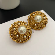 Front view of round pearl-style medallion clip-on earrings on a light display surface
