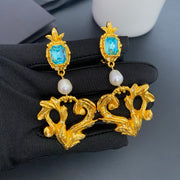 Front view of natural pearl and aqua lava heart clip-on earrings with gold-tone sculptural drops