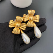 Close view of vintage-style gold-plated bow and pearl-style drop clip-on earrings