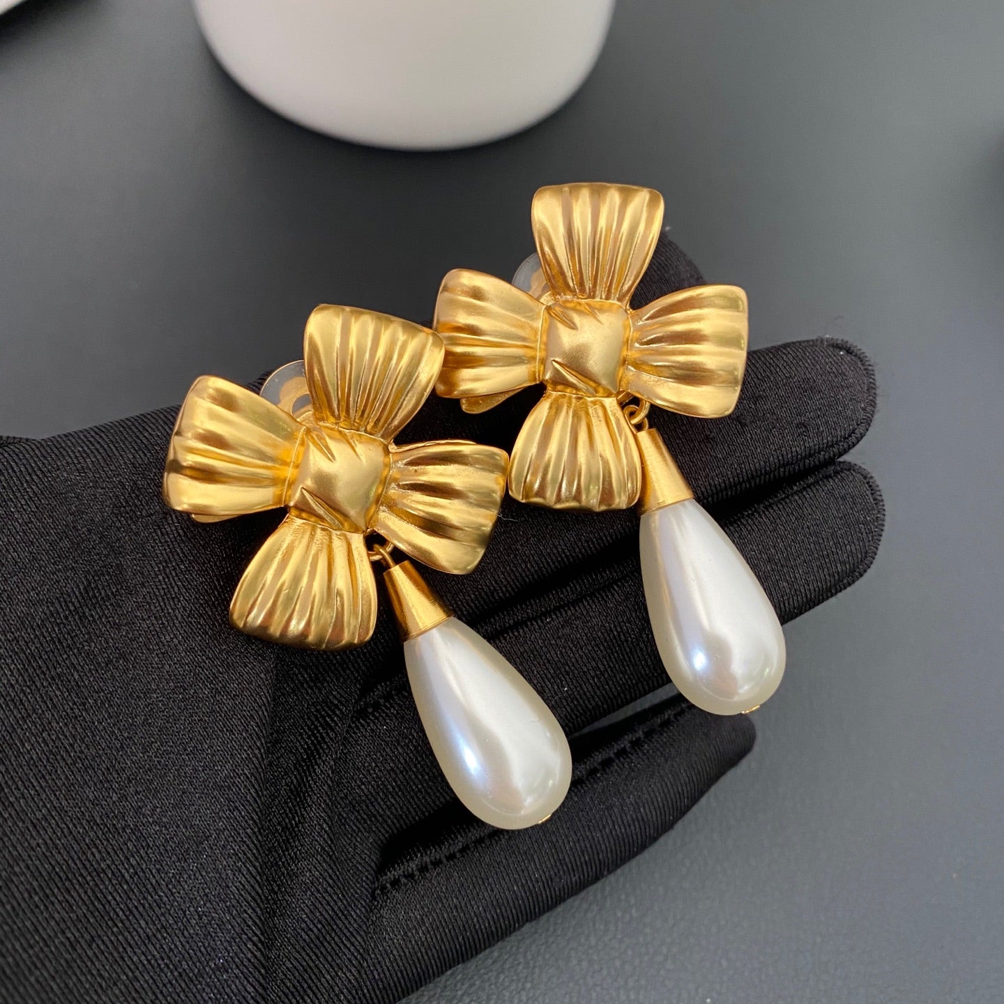 Close view of vintage-style gold-plated bow and pearl-style drop clip-on earrings