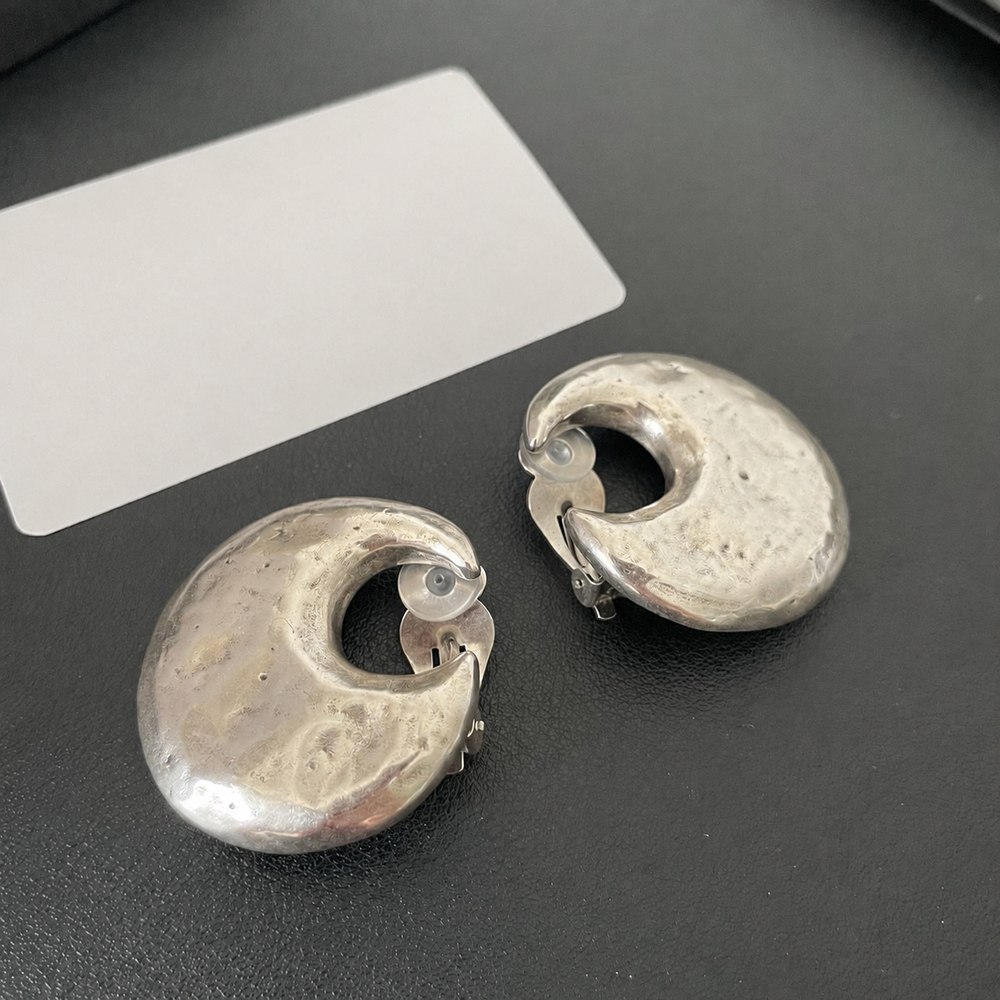 Front view of oversized silver-tone crescent moon clip-on earrings with a textured sculptural finish