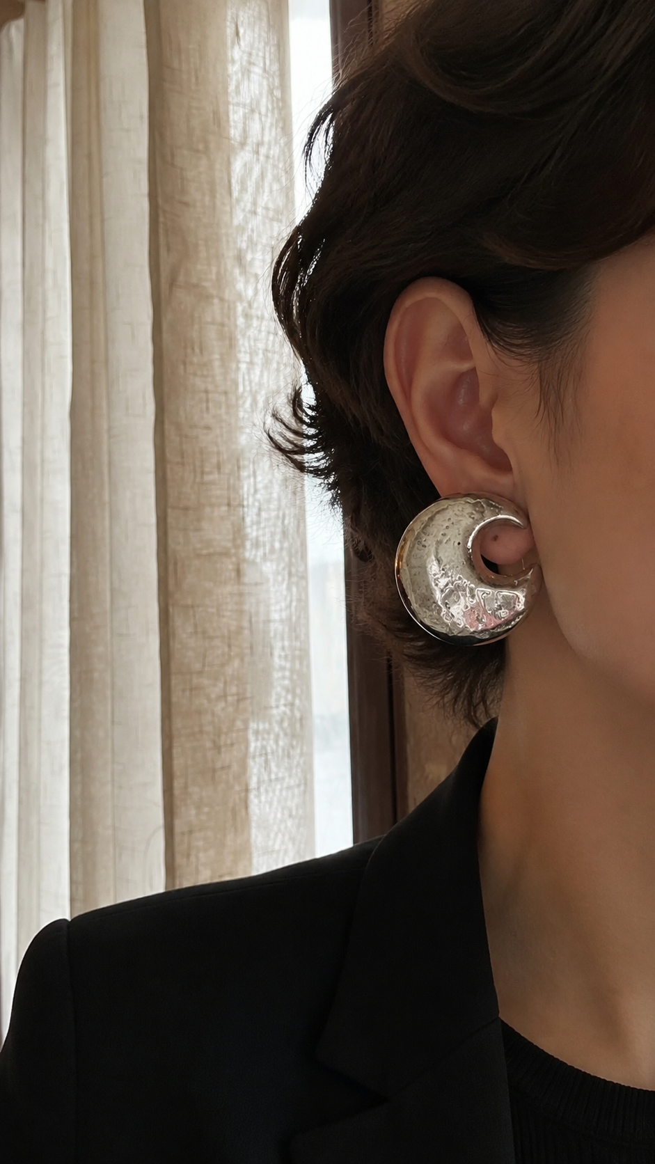 Model wearing an oversized silver-tone crescent moon clip-on earring