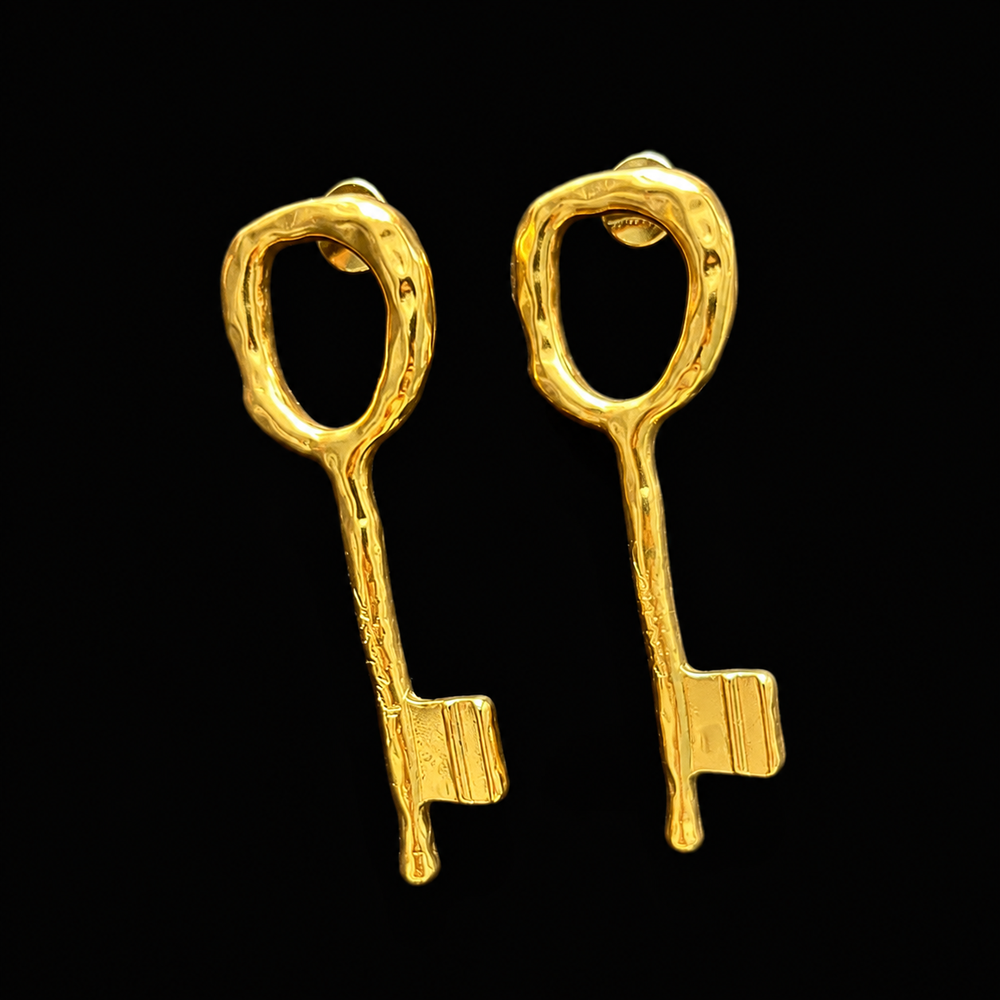 Front view of gold-tone key-shaped stud earrings on a black background
