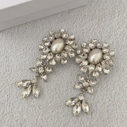 Full-length view of the floral pearl-style earrings and dangling leaf-shaped stone clusters