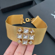 Close-up of the geometric square-stone centrepiece on the gold-tone mesh choker