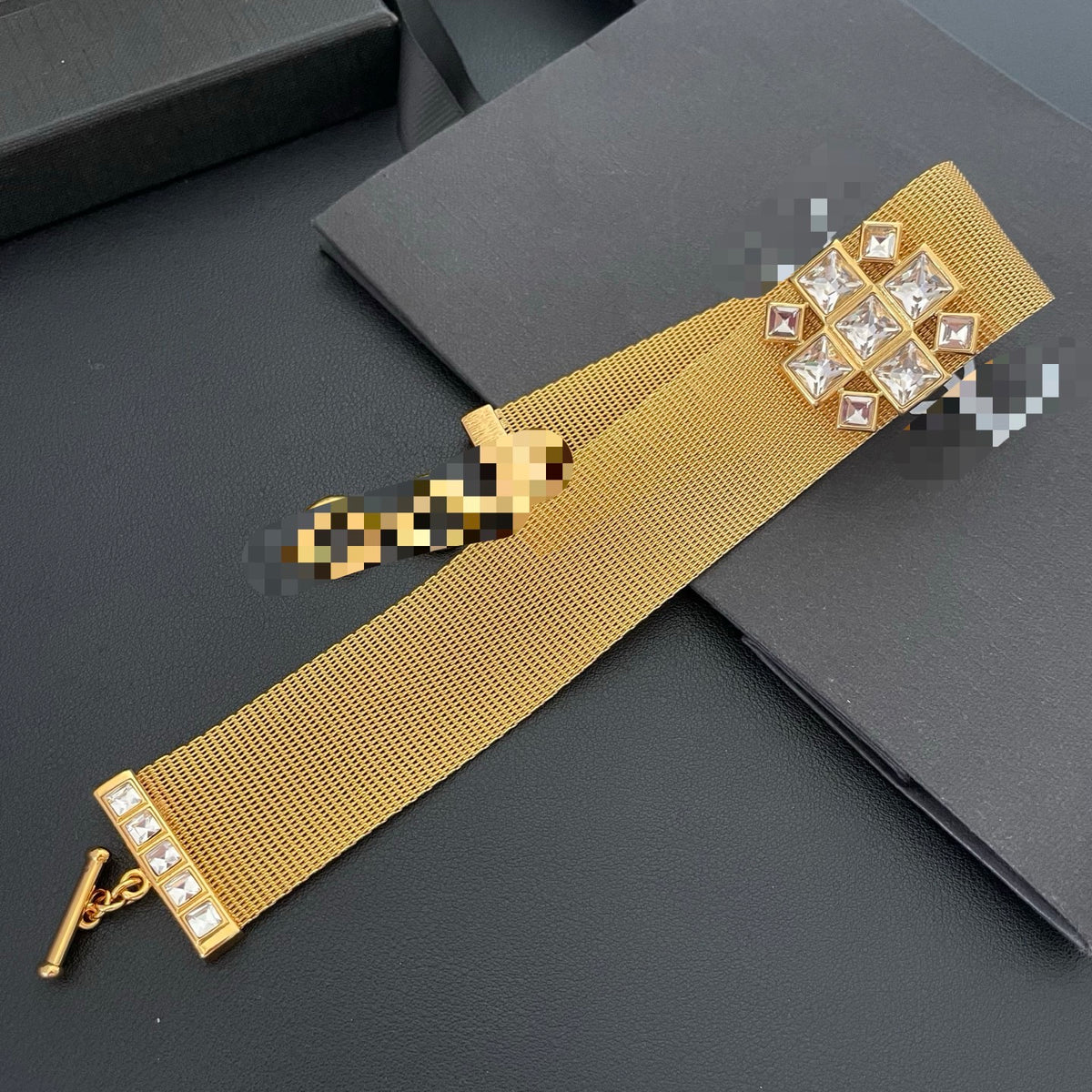 Gold-tone mesh choker laid flat showing the full band and toggle closure