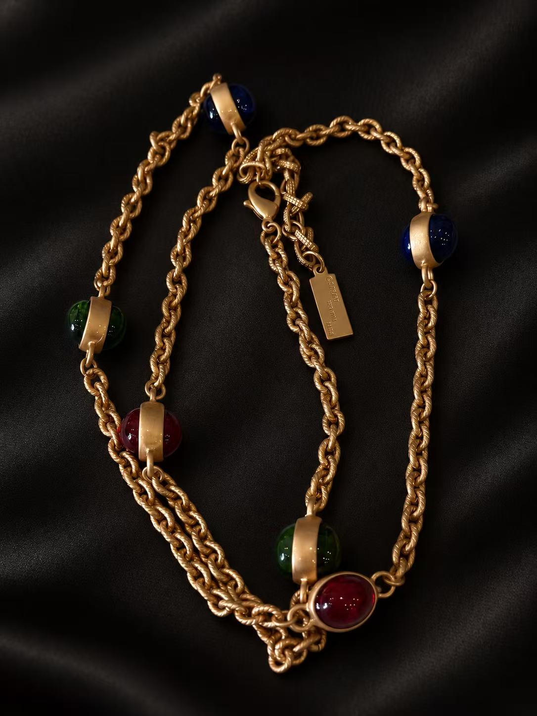 Close-up of the colorful domed glass accents and textured gold-tone chain links