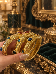 Hand-held view of gold-tone multicolor glass stretch bangles showing ribbed detail; sold individually