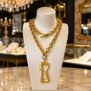 Gold-tone interchangeable keyhole pendant statement necklace displayed on a necklace bust
