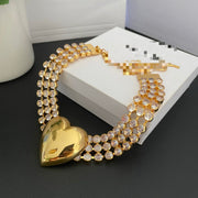 Gold-tone heart statement necklace with rows of clear crystal-style accents on a jewelry box