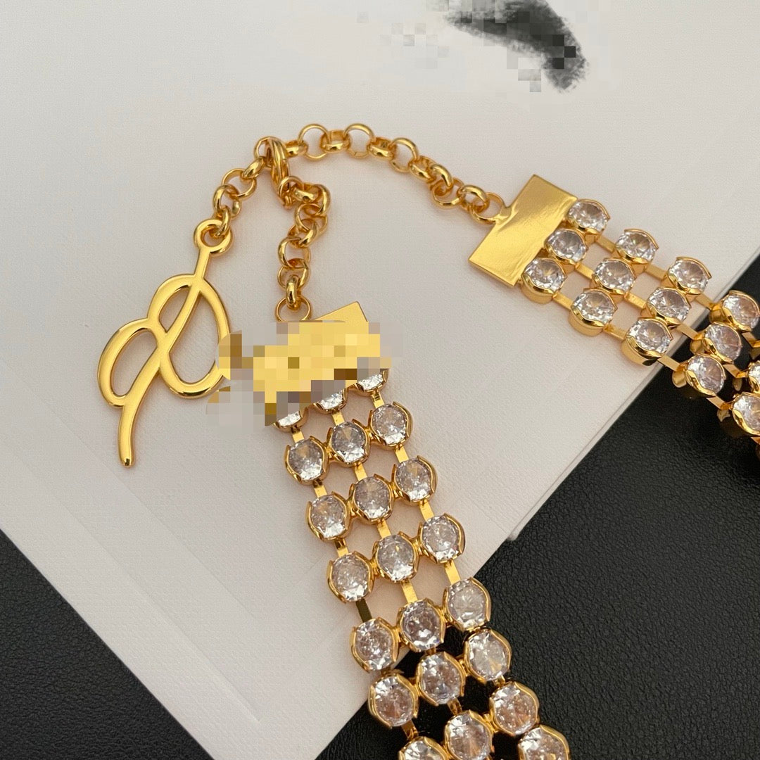 Close-up of the clasp, extender, and clear crystal-style rows on the gold-tone necklace