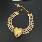 Full view of the gold-tone heart statement necklace with a multi-row crystal-style chain