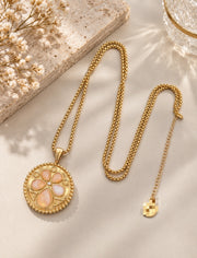 Full view of the 24K gold-plated medallion necklace laid on cream satin, showing the chain and extender