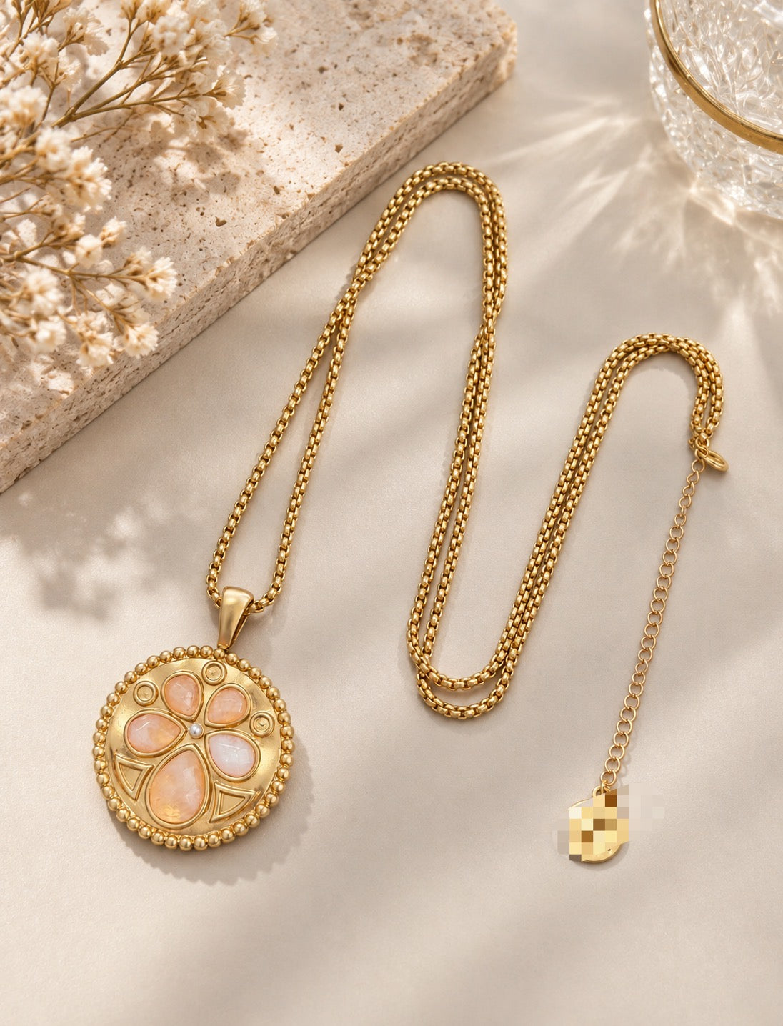 Full view of the 24K gold-plated medallion necklace laid on cream satin, showing the chain and extender