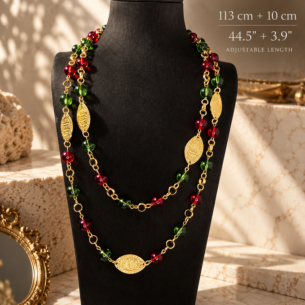 Vintage-inspired long red and green glass bead necklace with gold-tone oval medallions, shown layered on a black bust with a 113 cm plus 10 cm extender length label
