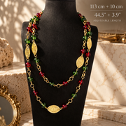 Vintage-inspired long red and green glass bead necklace with gold-tone oval medallions, shown layered on a black bust with a 113 cm plus 10 cm extender length label